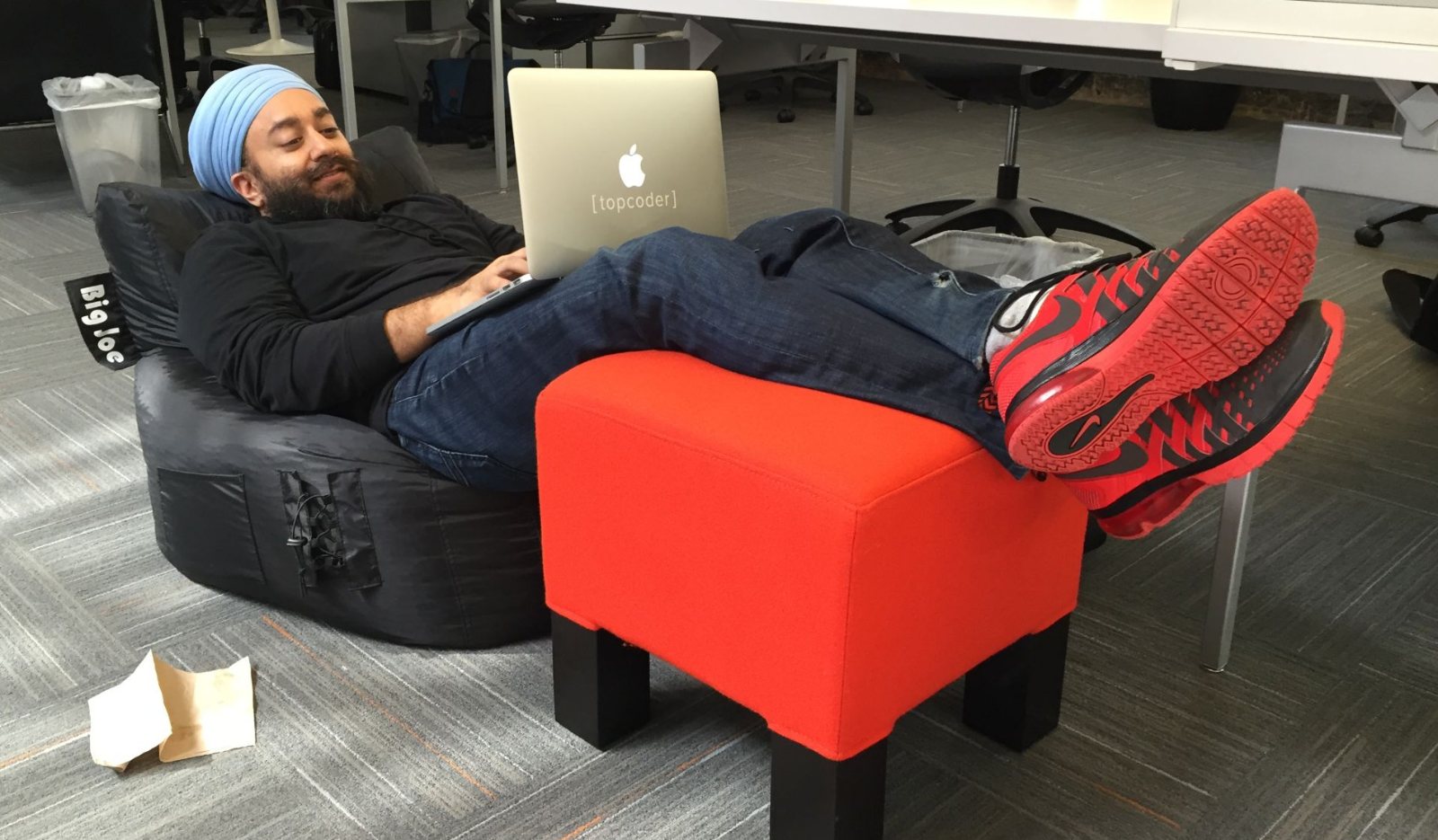 Narinder Singh at Topcoder, leaning back in a beanbag chair with a laptop, feet up on a red ottoman